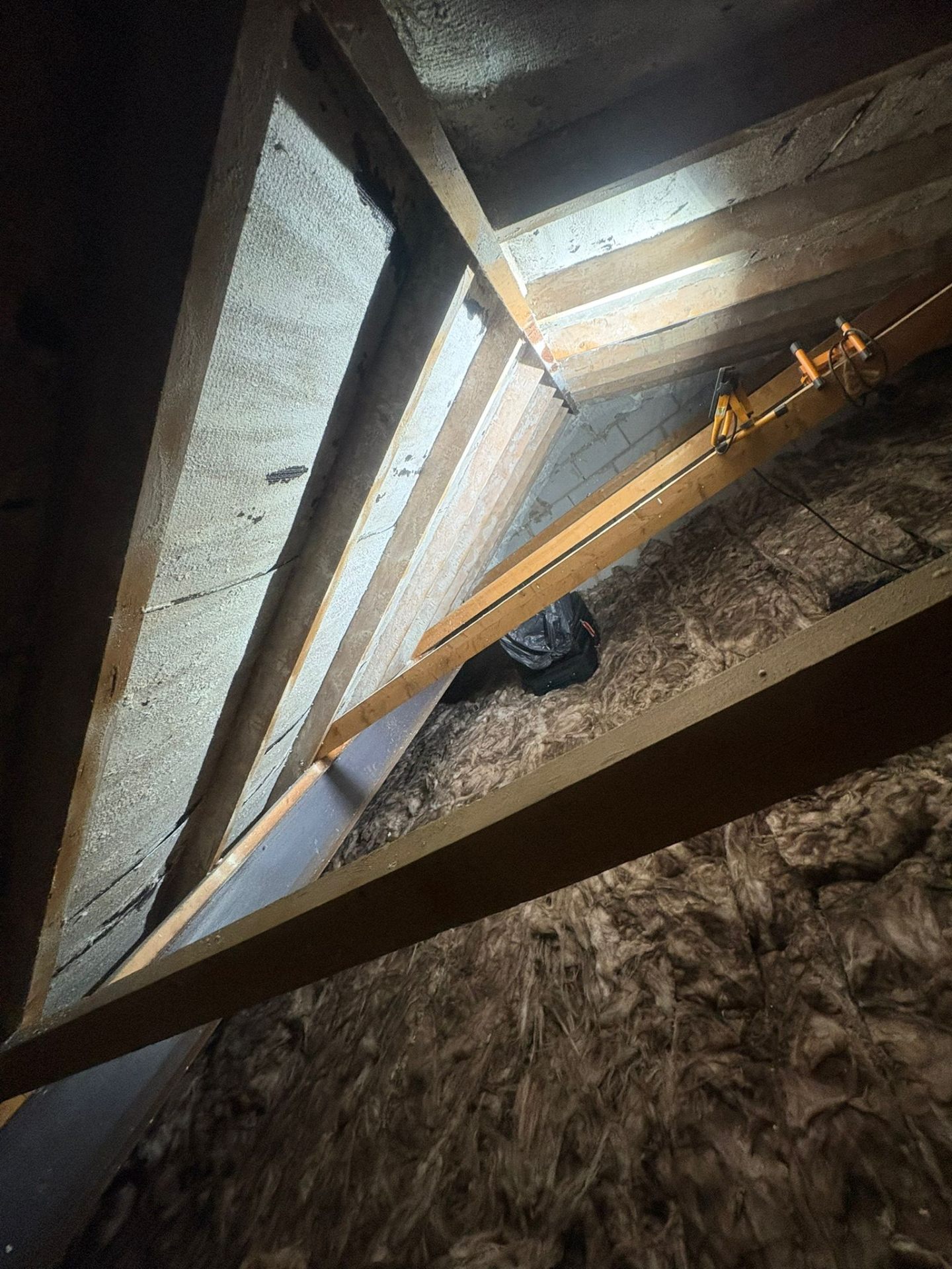 Spray foam coverage on roof slope viewed across joists and existing insulation