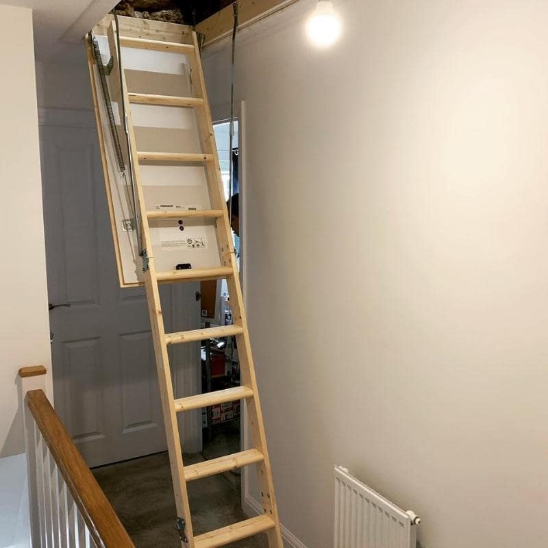 Boarded storage area around loft hatch with insulation tucked between joists